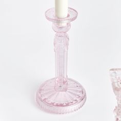 a pink glass candle holder with a white candle