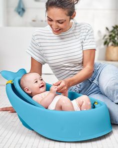 a woman playing with a baby in a blue bathtub on the floor next to a sink