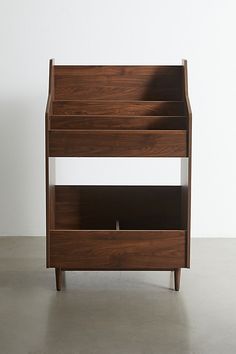 a wooden shelf sitting on top of a cement floor next to a white wall,