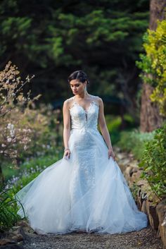 a woman in a wedding dress is walking down a path