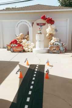 an entrance to a car themed birthday party with balloons and race cars on the road