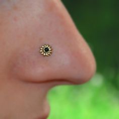 a woman's nose with a small black diamond in the shape of a sunflower