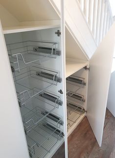 an open closet under the stairs with wire shelves on each side and drawers in between