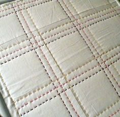 a close up of a quilt on a bed with red and yellow stitching in the middle