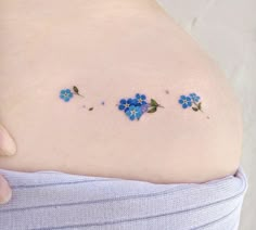 a woman's stomach with blue flowers painted on the back of her belly and side