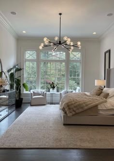 a bedroom with a large bed and two chairs in front of a window that overlooks the trees