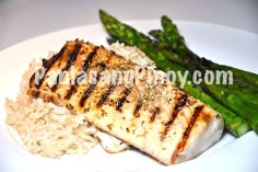 grilled fish with rice and asparagus on a white plate