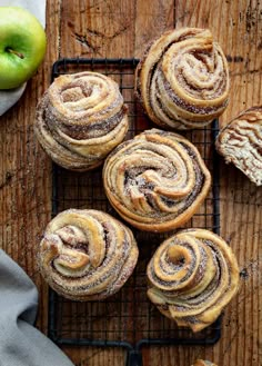 cinnamon rolls on a cooling rack with an apple in the background