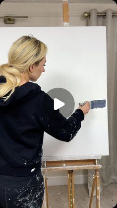 a woman is painting on a white board