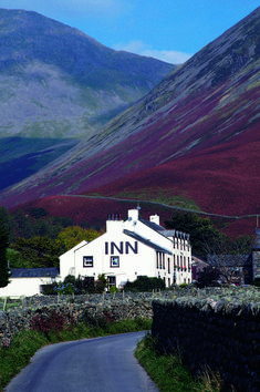 a white building sitting on the side of a road next to a lush green hillside