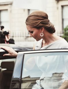 a woman in a white dress is getting out of a car