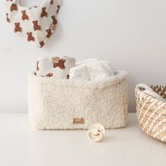 a basket with some cloths in it next to a wall hanging on the wall