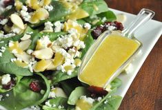 spinach salad with cranberries and feta cheese dressing on a white plate