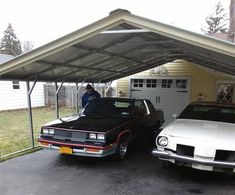 two cars parked in front of a garage with a man working on the roof above them