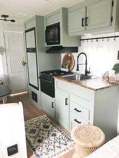 a kitchen with green cabinets and black appliances