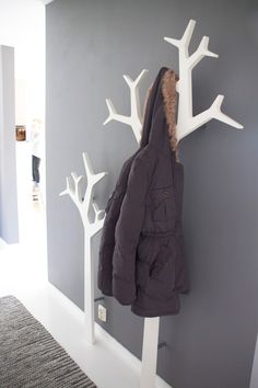 a coat rack with two coats hanging from it's sides next to a gray wall