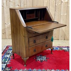 an old wooden desk with a drawer on the top and a red rug underneath it