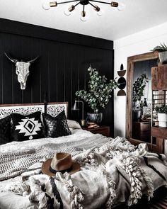 a bedroom with black walls, white bedding and an animal head on the wall