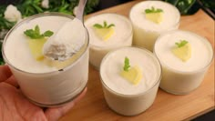 a person is holding a spoon with some desserts in it on a wooden tray