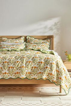 a bed with green and yellow bedspread in a room next to a table