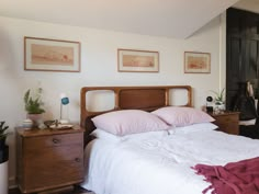 there is a bed with pink pillows and blankets on the headboard in this bedroom