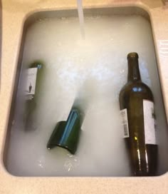 two bottles in a sink filled with water