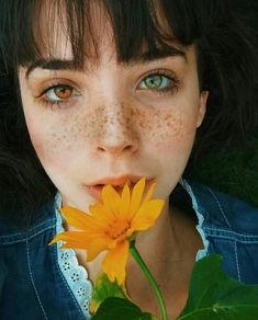 a woman with freckles on her face holding a flower