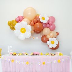 a table topped with balloons and flowers next to a wall mounted balloon art piece on the wall