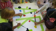 several children are painting on a large piece of paper