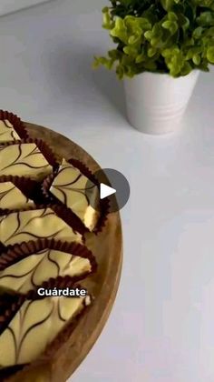 there is a cake with chocolate and white icing on the plate next to a potted plant