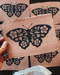 a person holding up some paper with black and white butterflies on it