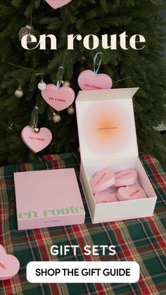 the gift set is on display in front of a christmas tree with hearts hanging from it