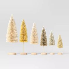 five small trees are lined up in different colors and sizes, each with their own wooden base