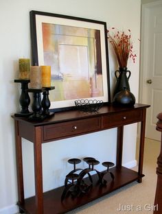 a console table with two vases and candles on it in front of a painting