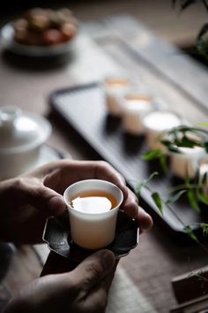 a person holding a cup of coffee on top of a wooden table