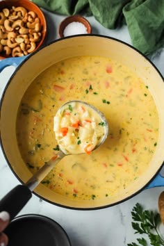 a ladle full of soup with cashews and other foods in bowls around it