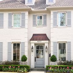 a white house with gray shutters and flowers in front