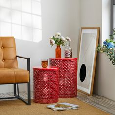 two red side tables with vases and flowers on them in front of a window