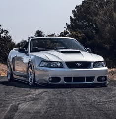 a silver sports car parked on top of a dirt road