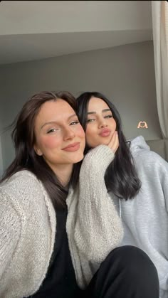 two women sitting next to each other in front of a window