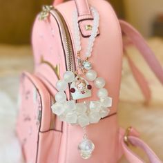 a pink handbag with some charms attached to it