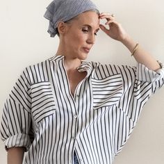 a woman wearing a white and black striped shirt with a head scarf on her head