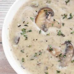 a white bowl filled with mushroom soup on top of a wooden table