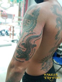 the back of a man with tattoos on his arm and shoulder is covered in black ink