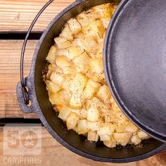 an iron skillet filled with potatoes on top of a wooden table