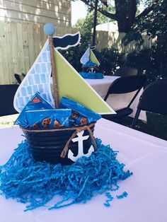 a table topped with a basket filled with blue yarn and a sailboat decoration on top of it