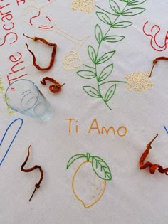 the table cloth has been embroidered with letters and fruit on it, along with other handmade items