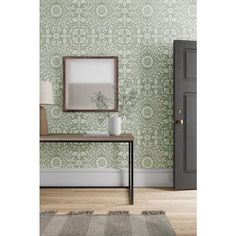 a room with green wallpaper and a table in front of the door that has a mirror on it