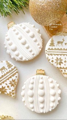 three white and gold christmas ornaments on a table