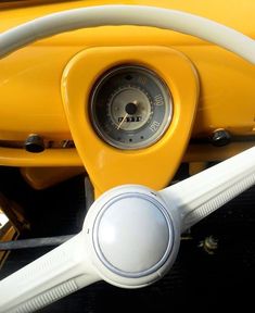 the steering wheel and dashboard of a yellow motor scooter with white spokes